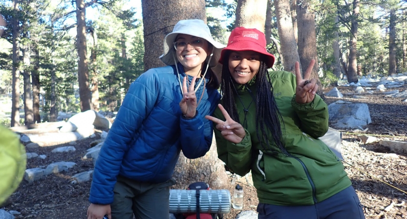 two students smile and give peace signs on a backpacking trip for bipoc teens with outward bound